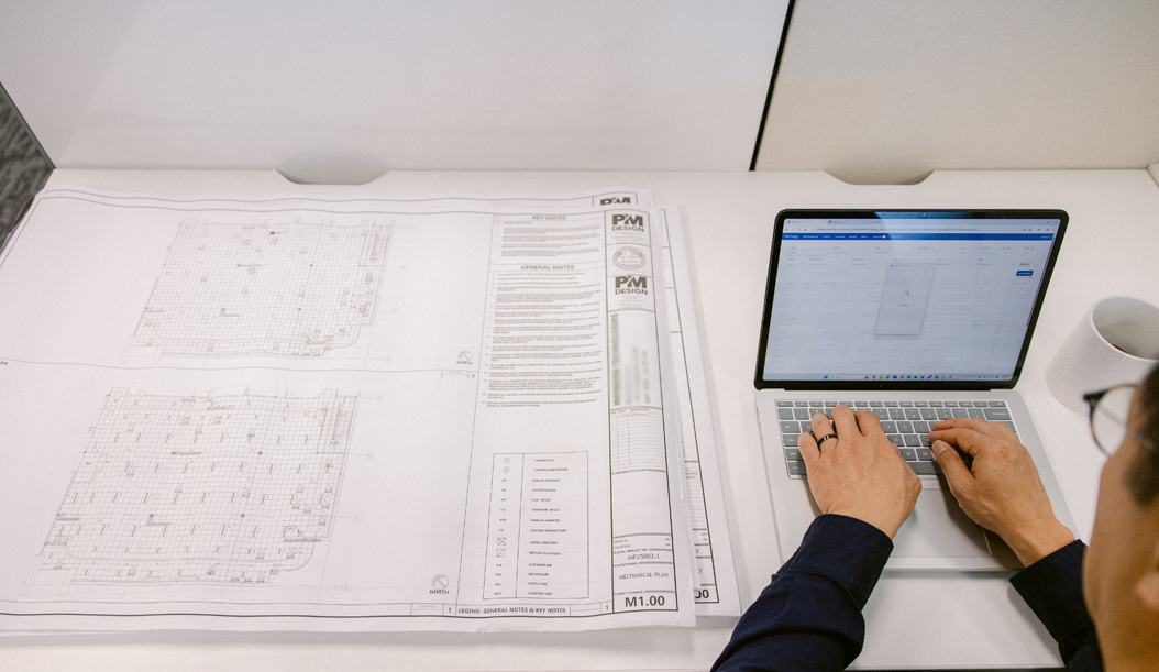 overhead view of architectural drawings and a laptop